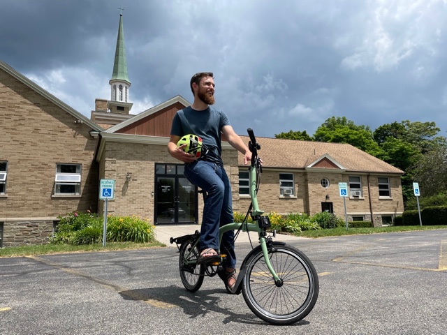 Me on a Brompton folding bike in the parking lot of my church.